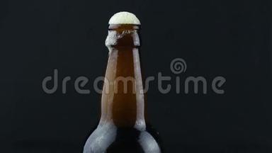 啤酒泡沫沿着一瓶雾蒙蒙的啤酒流下来。 啤酒泡沫顺着一瓶深色啤酒流下来..
